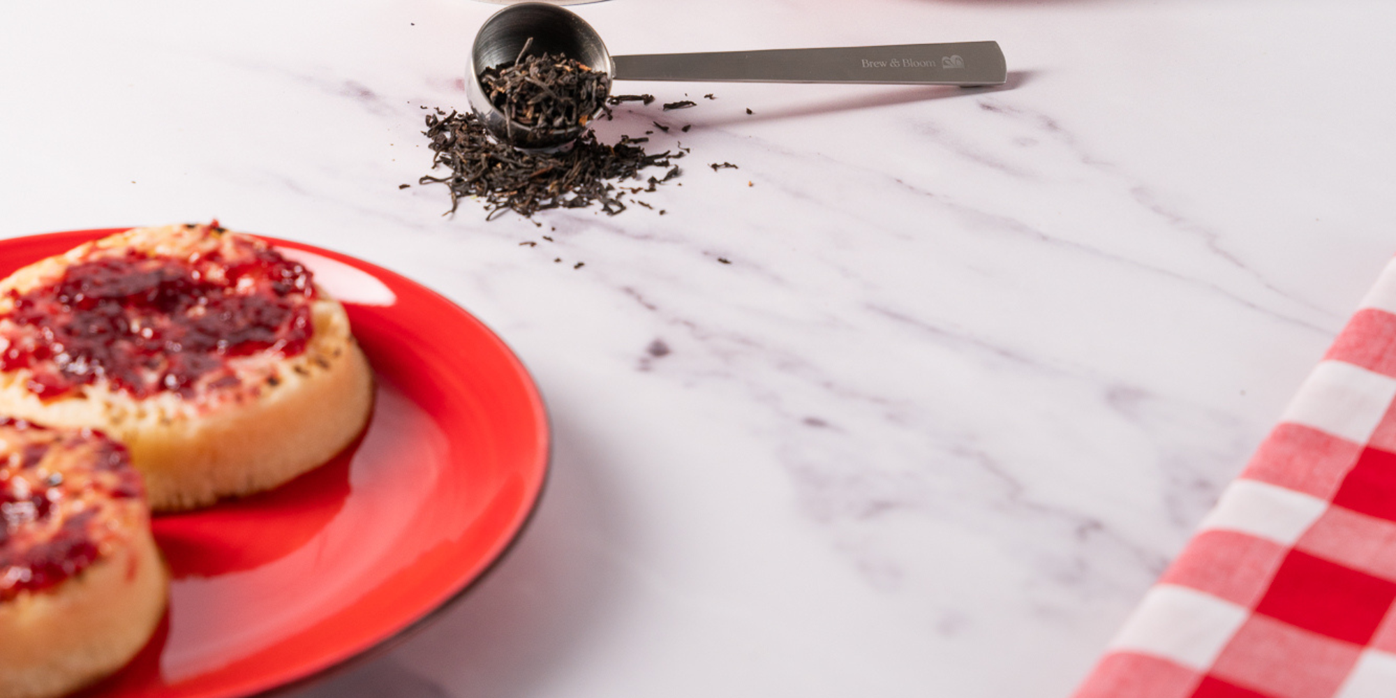 Loose leaf breakfast tea with jam on toast on a red plate, styled for Brew & Bloom morning ritual