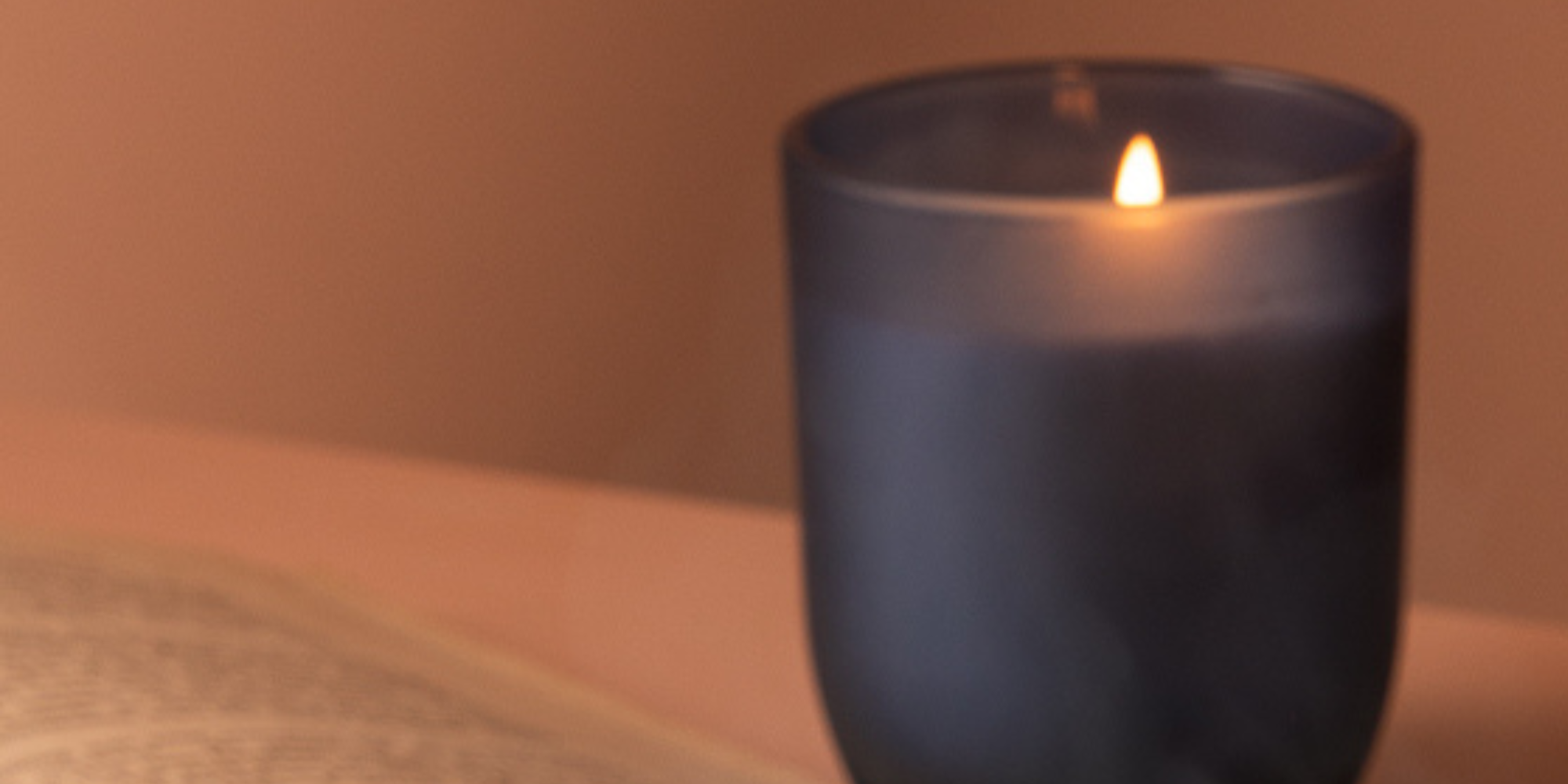 Lit candle beside evening tea, creating a calm Brew & Bloom wind-down moment
