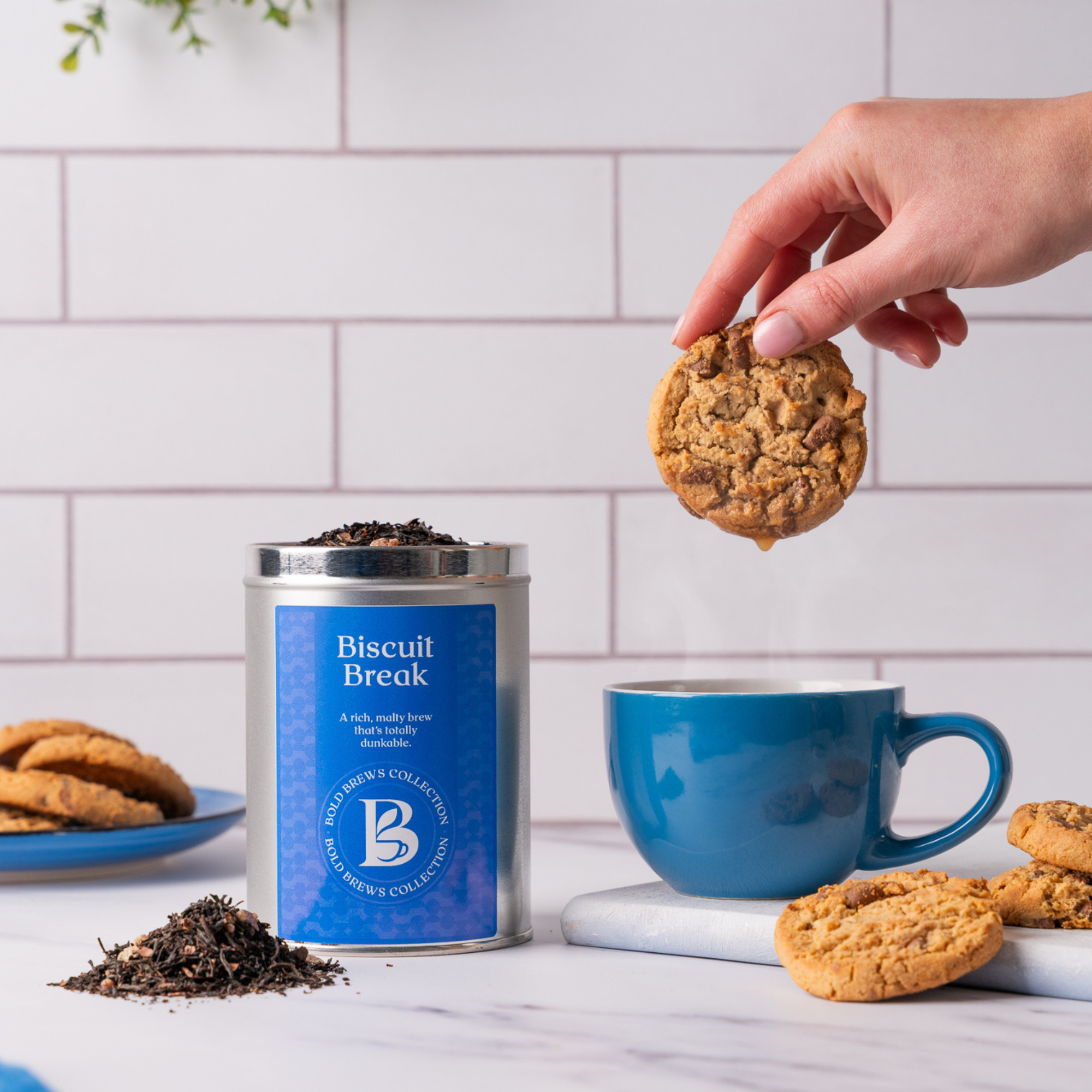 Biscuit Break loose leaf black tea with blue mug and biscuit dunking moment